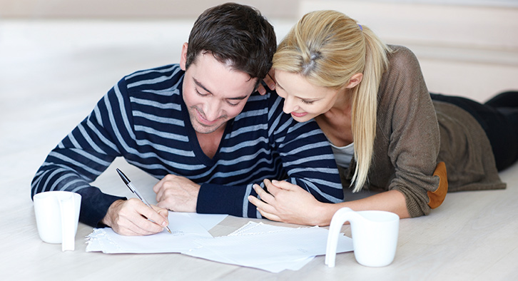 a couple laying on the ground looking at financial paperwork