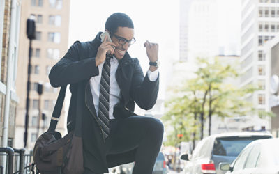 Businessman talking on cell phone in city and celebrating