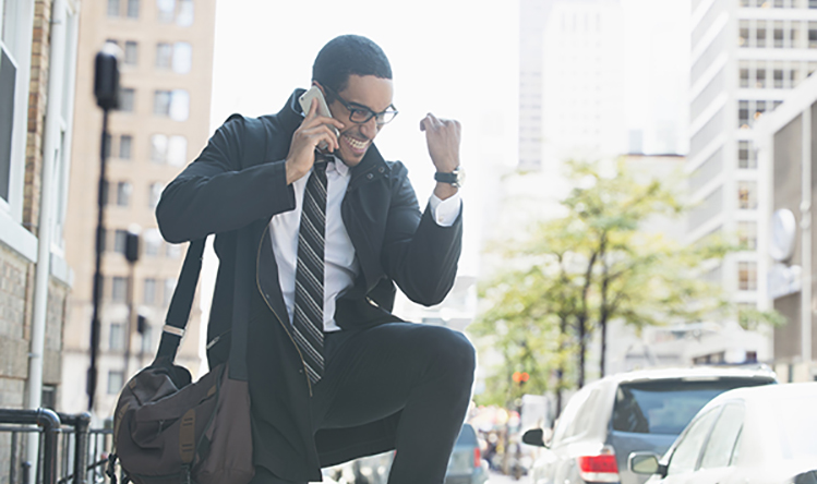 Businessman talking on cell phone in city and celebrating