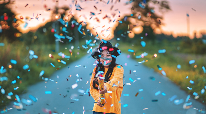 girl in yellow shirt shooting off confetti flying everywhere