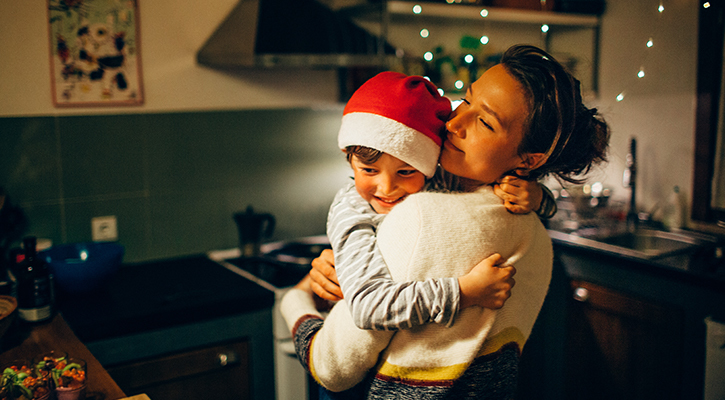 mother holding son with a santa hat relaxing at home